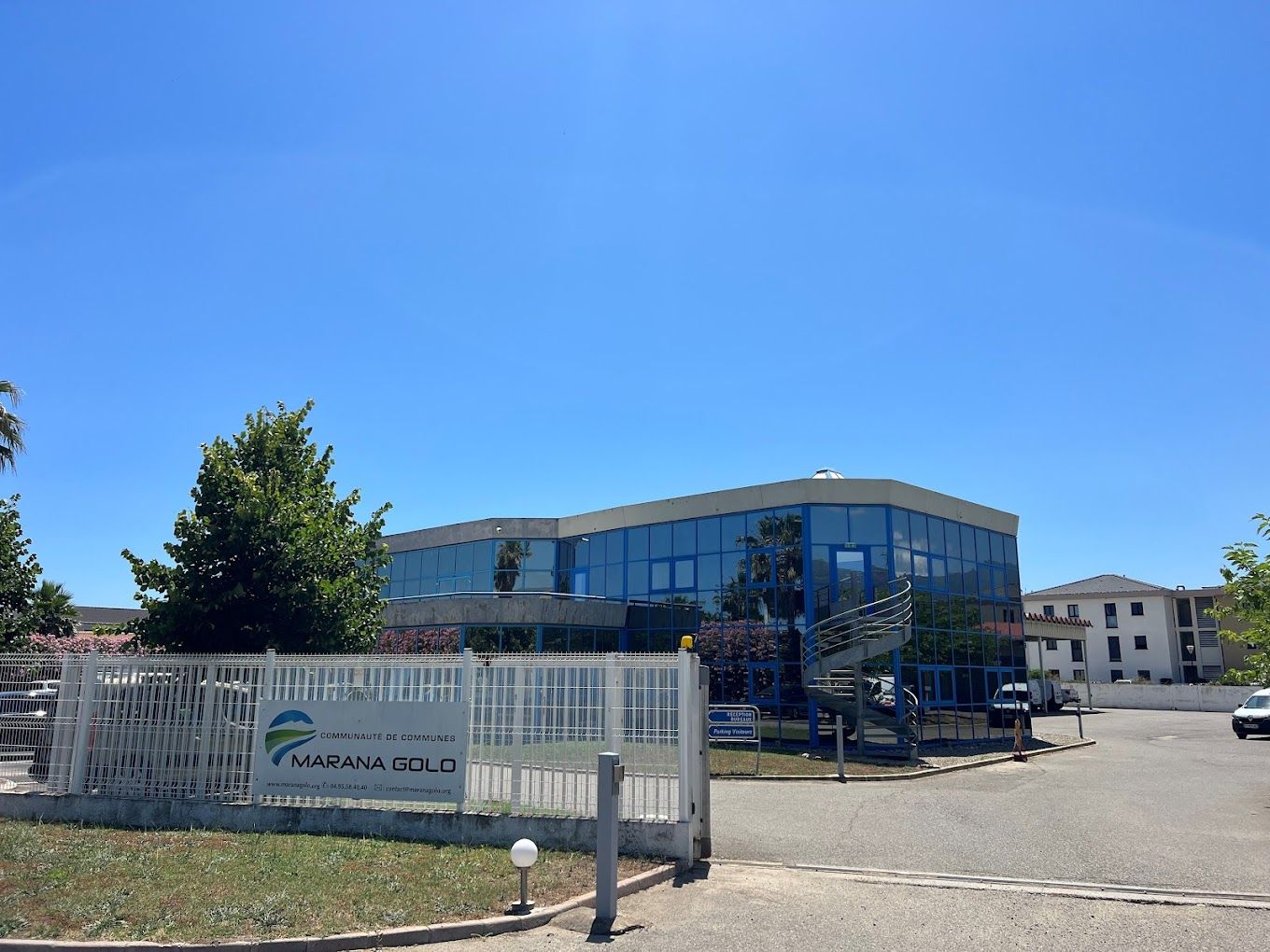 Bâtiment en verre avec un portail blanc et le logo de la Communauté de communes Marana Golo dessus