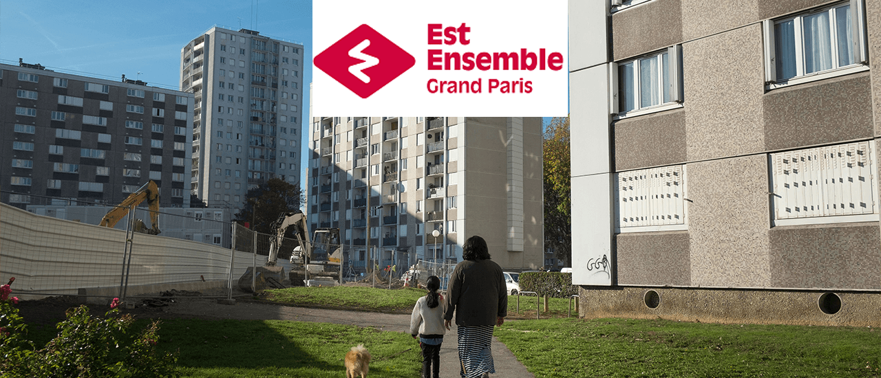 2 personnes et un chien de dos entre des immeubles en travaux